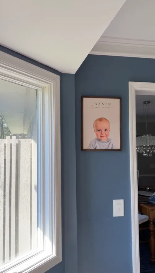 Framed portrait of Jaxson hanging on a slate blue wall